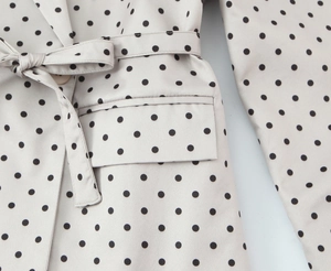 Gros plan détaillé du blazer beige à pois avec ceinture et rabat de poche texturé