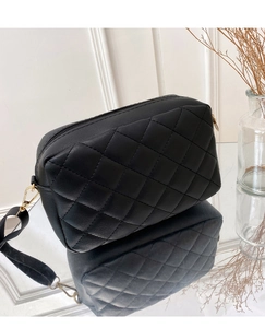 Detail of black quilted crossbody bag with rhombic pattern and gold metal hardware
