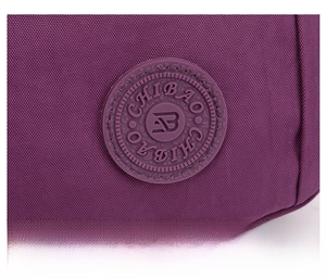 Primer plano detallado de un bolso de nailon morado con logotipo redondo de goma y tejido texturizado