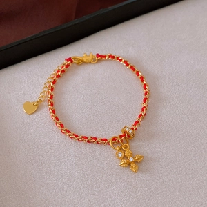 Detail of red rope bracelet with gold-plated heart, zircon ring and cross vajra charm
