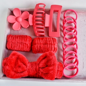 Flat lay of red and pink hair accessory set including bow headband and claw clips