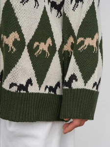 Close-up of ribbed cuffs and horse jacquard pattern on a green argyle knit sweater