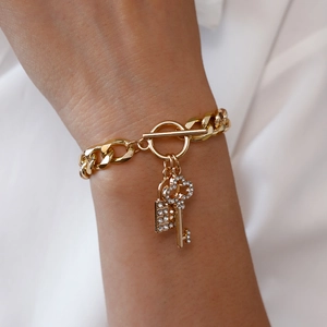 Macro shot of gold OT buckle bracelet with rhinestone lock and key charms on wrist