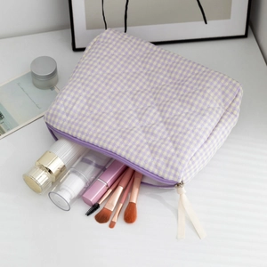 Detailed view of quilted plaid makeup bag showing capacity with brushes and skin care bottles