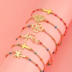 Colorful beaded stainless steel bracelets with assorted gold charms on a pink stand