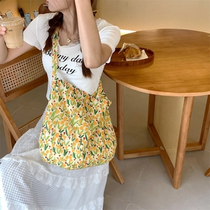 Detailed close-up of yellow tulip floral canvas tote bag in a casual cafe setting