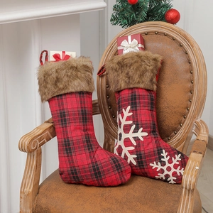 Lot de deux chaussettes de Noël à carreaux avec bordure en fourrure sur un fauteuil en cuir