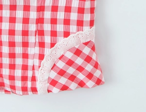 Dettaglio ravvicinato del tessuto vichy bianco e rosso con bordo in pizzo bianco