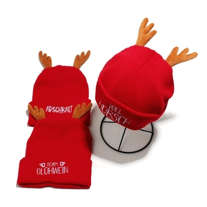 Red Christmas knit beanies with reindeer antlers and white embroidered German text