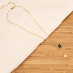Detail of gold emerald necklace with paperclip chain and polished round pendant charm