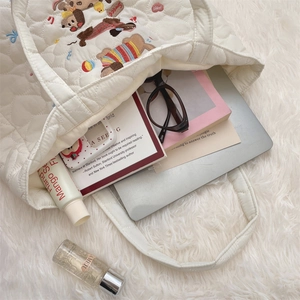 Quilted tote bag detail with cute puppy embroidery on soft white plush surface