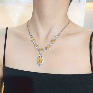 Close-up of luxury necklace with yellow teardrop gemstone and silver metal on model