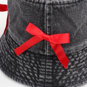 Detail of a dark denim bucket hat featuring a red satin bow and quilted stitching