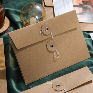 Vintage kraft paper envelope file folder with string tie closure on green velvet
