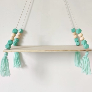 Detail of wooden wall shelf with mint green geometric beads and decorative tassels