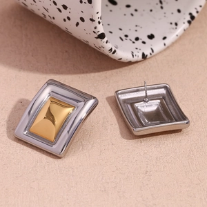 Macro view of geometric rectangular stud earrings featuring two-tone gold and silver finish