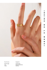 Close-up of a gold-plated geometric ring with sunburst emblem worn on a finger