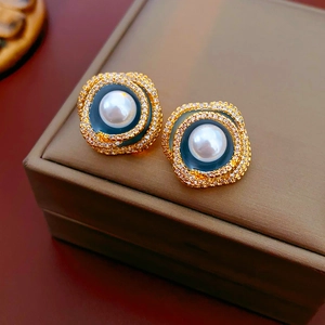 Macro shot of vintage round pearl earrings with rhinestone halo and blue enamel inlay