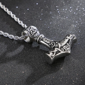 Detail of Viking Thor Mjolnir pendant with skull motif and twisted chain on black surface