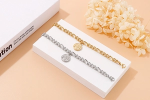 Close-up of gold and silver tree of life pendants on elegant Figaro chain bracelets