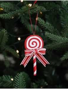 Close-up of red and white spiral lollipop Christmas ornament with striped bow