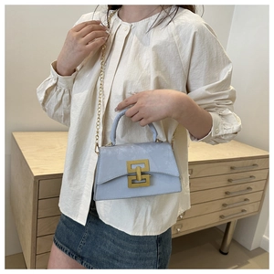 Detail of light blue square crossbody bag with gold chain strap and H-shaped buckle