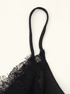 Detailansicht der zarten Spitze und des seidigen Satinstoffs an einem schwarzen Trägerkleid