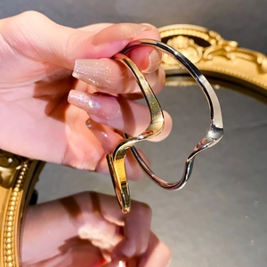 Detailed view of polished wavy metal bracelets in gold and silver finishes on a model