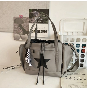 Detail of grey waterproof nylon tote with black star print and checkered charm