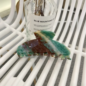 Detail of a large marble texture acetate hair claw clip with green and brown patterns