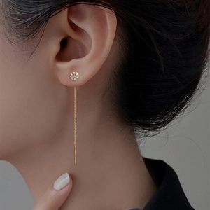 Close-up of golden long chain tassel earring with sparkling zircon snowflake stud