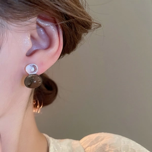Close-up of minimalist translucent gray spherical stud earrings worn on model's ear