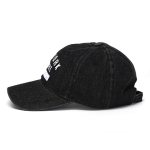 Detail view of New York embroidery on a black washed denim baseball cap with side profile