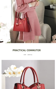 Detail view of red faux leather handbag featuring cherry charm and golden hardware detail