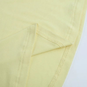 Gros plan du tissu tricoté jaune clair montrant les détails de couture du double ourlet
