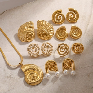 Detail shot of golden shell and spiral jewelry set with rhinestones and pearls on stone