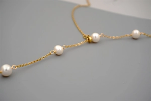 Macro view of adjustable titanium chain with glossy freshwater pearls and gold plating