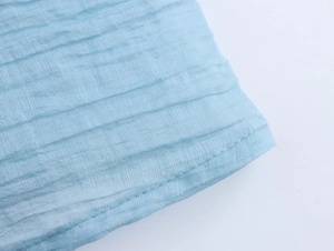 Detailed close-up of light blue pleated fabric texture with neat stitching on a long dress