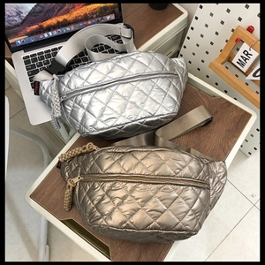 Detailed shot of quilted metallic waist bags in silver and gold on a wooden desk