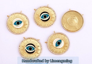 Macro detail of gold plated evil eye pendant charms with micro paved white zircon stones
