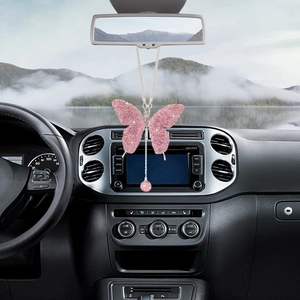 Sparkling pink rhinestone butterfly car mirror pendant hanging in a modern vehicle interior