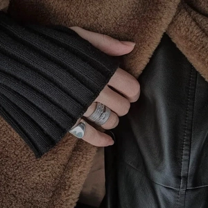 Detail of diverse silver texture rings worn by model on a professional leather backdrop