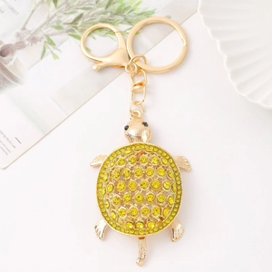 Detail of a sparkling golden turtle keychain with yellow rhinestones and cat eye stones