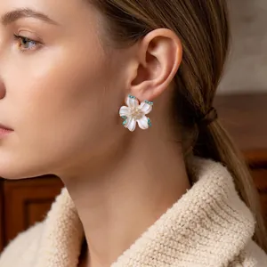 Vintage floral stud earrings with white petals and gold trim worn by a model