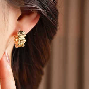 Macro detail of gold irregular hoop earring with textured molten finish on the ear