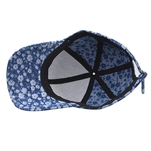 Internal detail of denim baseball cap with white floral pattern and adjustable metal buckle
