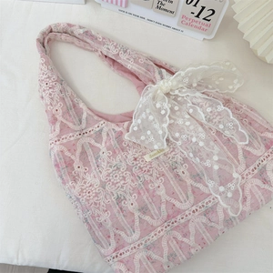 Close-up of pink canvas tote bag featuring delicate white lace embroidery and bow