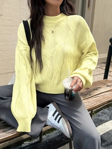 Detailed cable knit texture and ribbed cuff on a yellow casual crewneck sweater