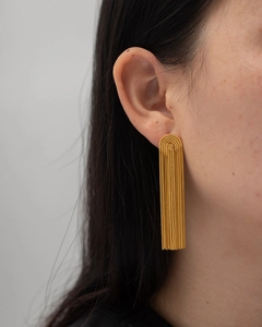 Close-up of a model wearing long golden tassel earrings with fine chain tassels