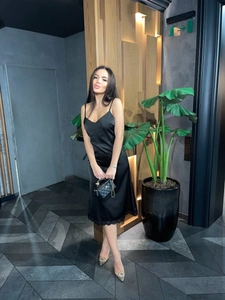 Detailed view of black satin slip dress with exquisite lace trim on the hemline